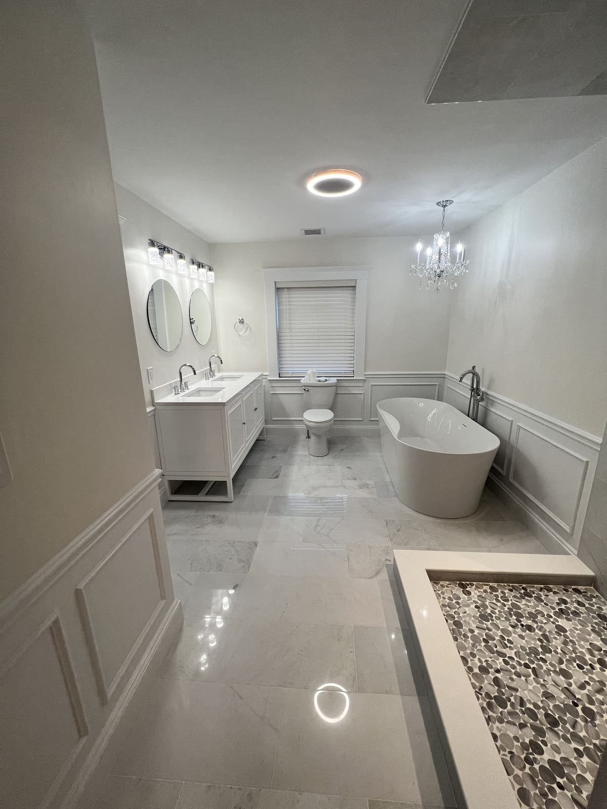 Remodeled bathroom with freestanding tub and pebble-floor shower plumbed by Precision Plumbing Solutions
