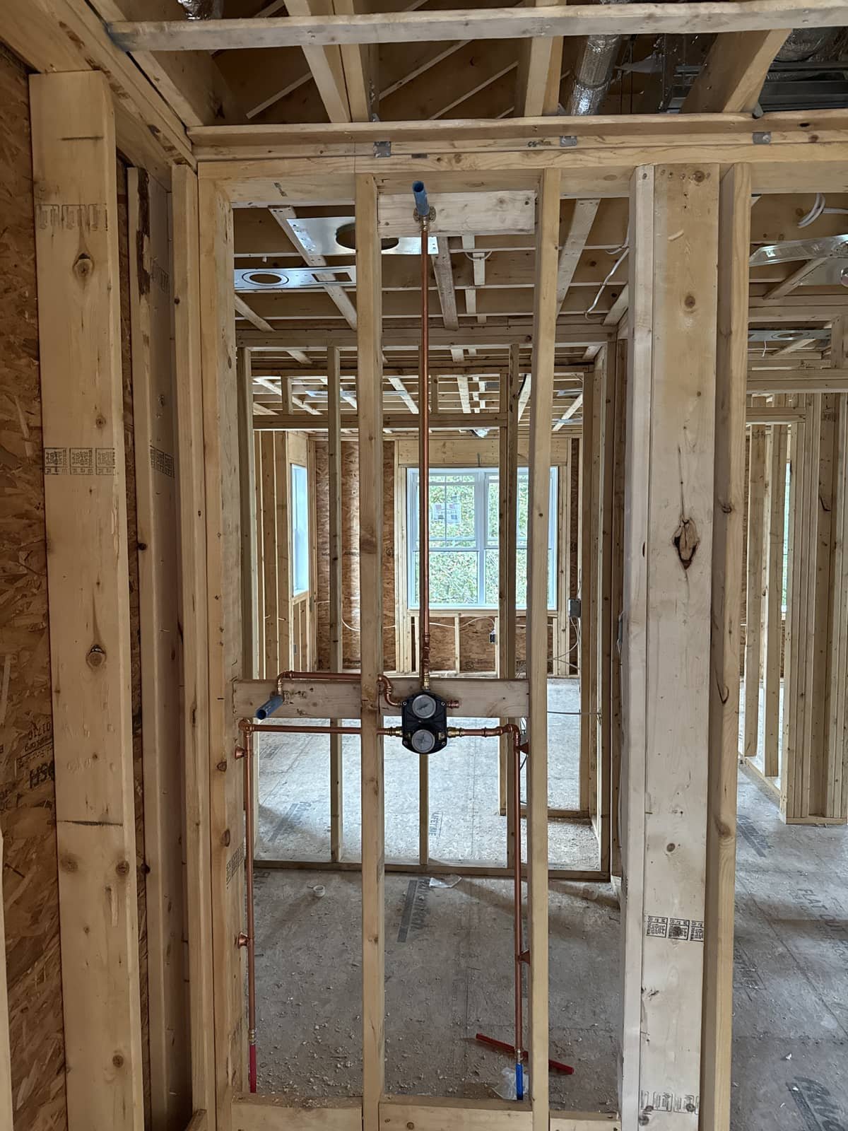 Rough-in plumbing lines run through new construction framing by Precision Plumbing Solutions